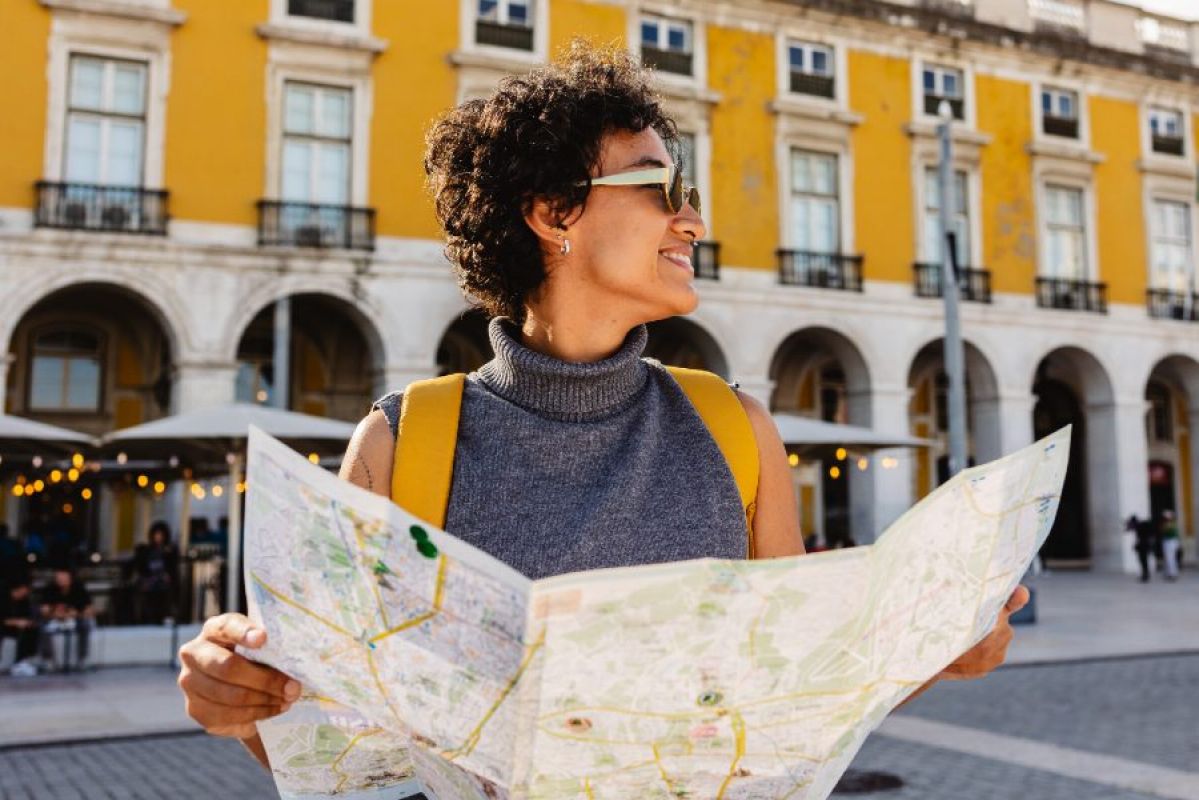 young woman smiling in sunglasses holding a map in Lisbon