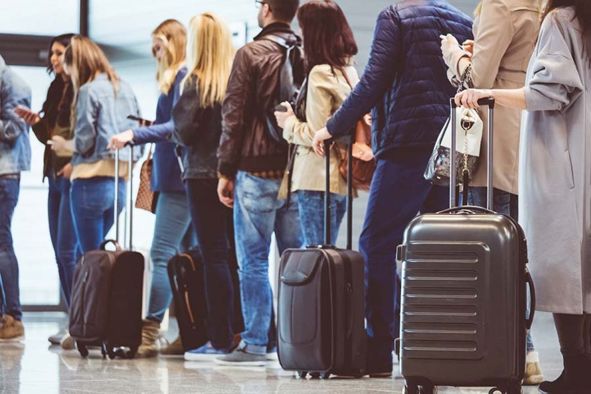 people lining up with bags to check in at airport