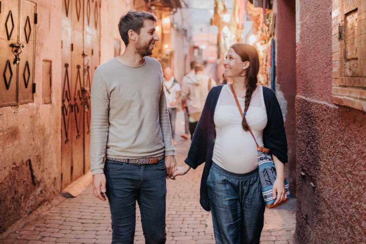 young man and pregnant woman holding hands while travelling