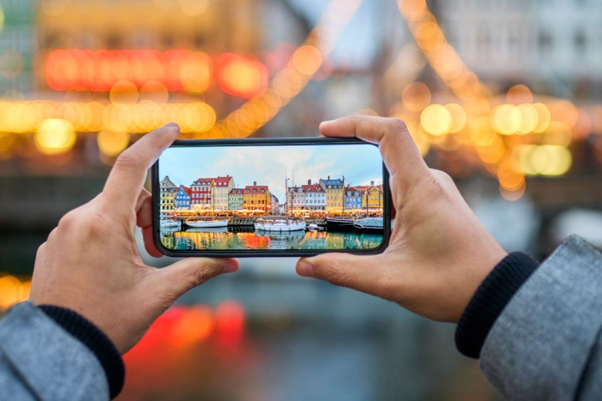 man taking a photo of Danish houses on his smartphone