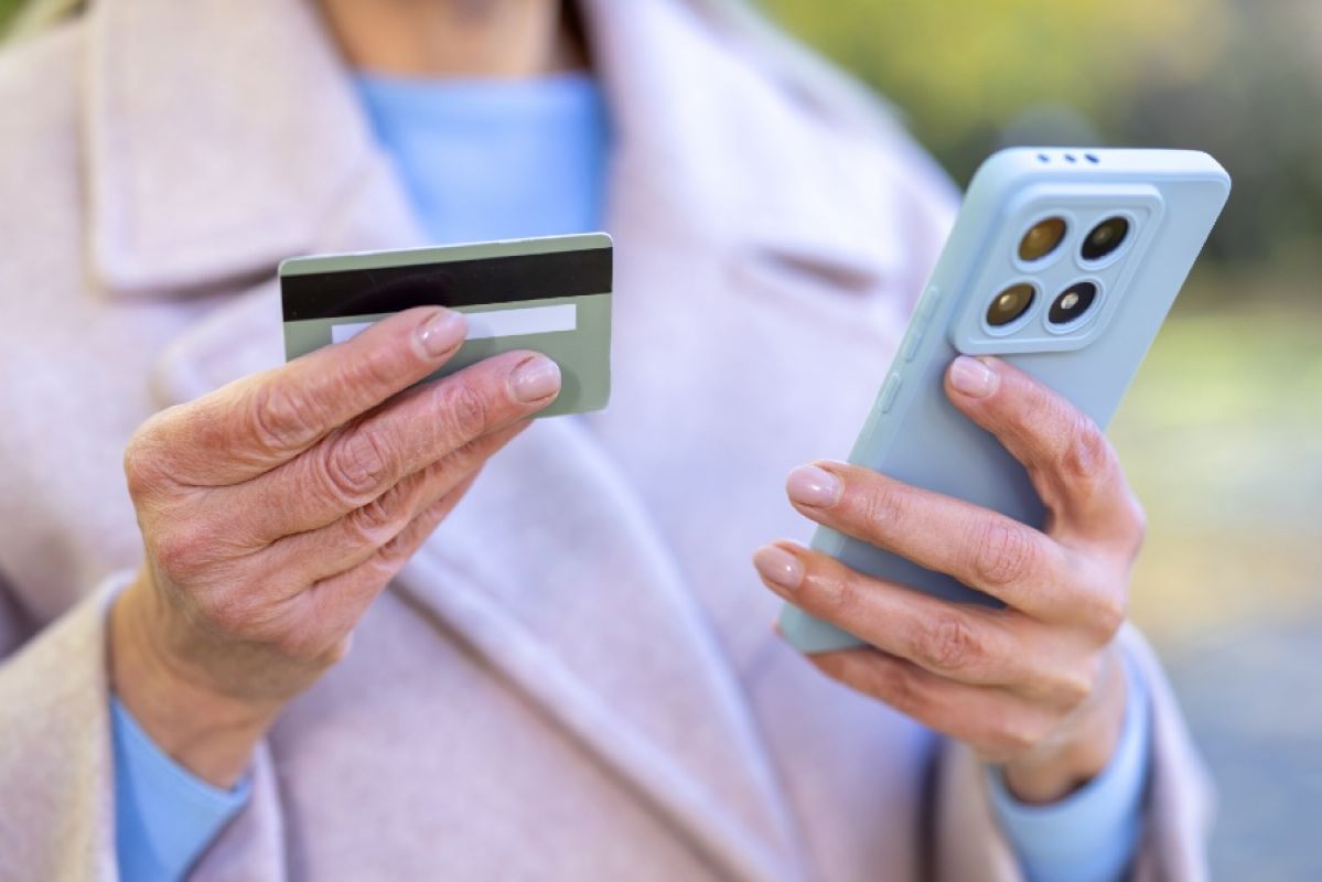 older woman holding a credit card and a smartphone