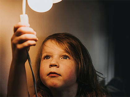 Young child flicks the switch on a lamp.