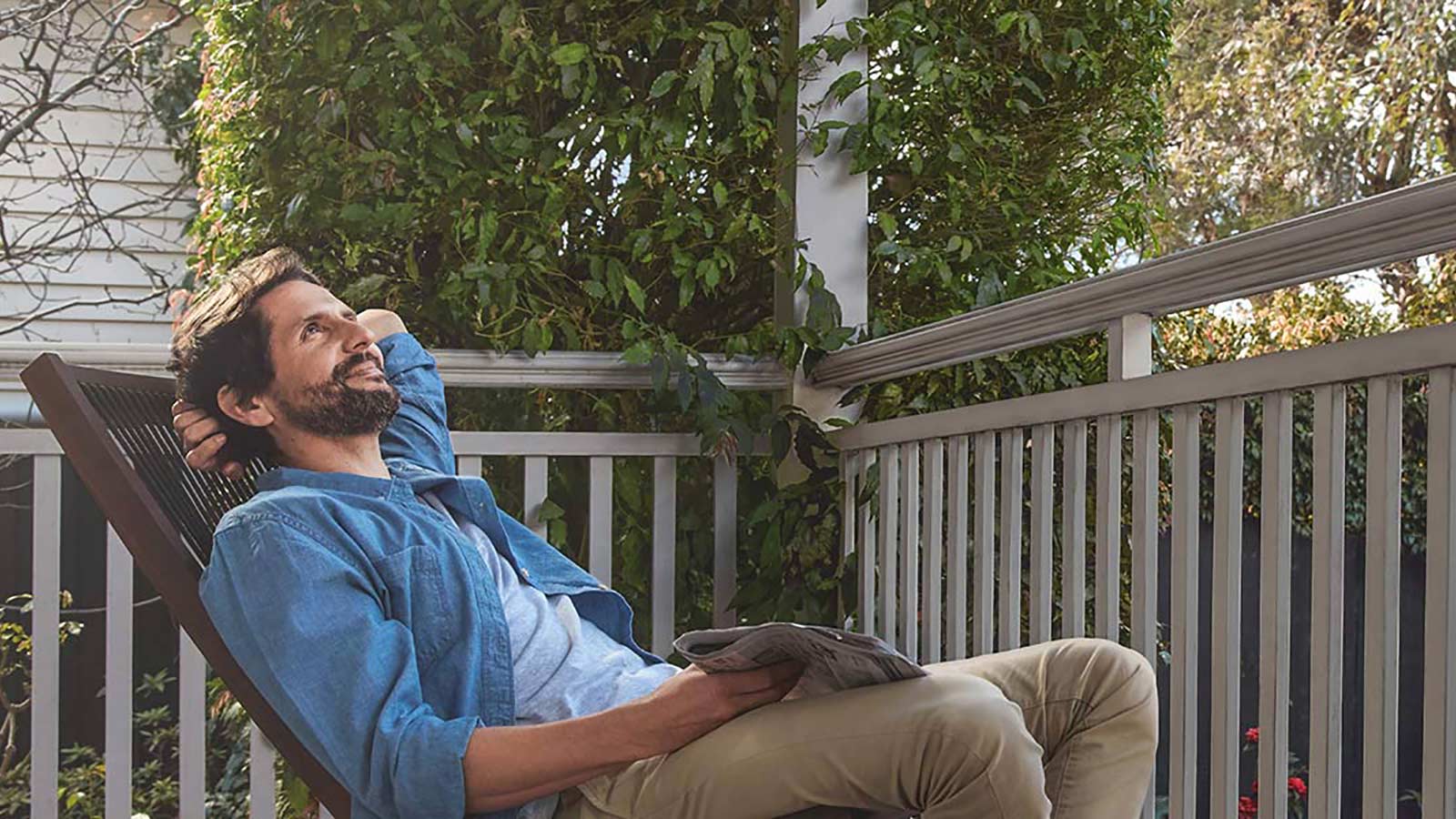 Man relaxing on balcony holding a newspaper