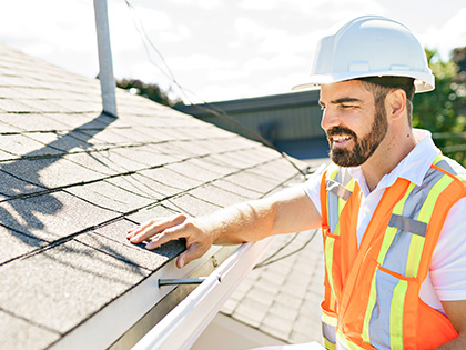 Man in a hardhat and high-vis vest inspecting a house during a building inspection. 