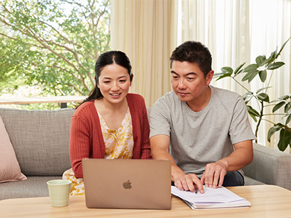 Couple smiling while researching on their laptop.