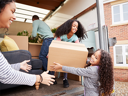 Family lifting boxes out of a moving truck.