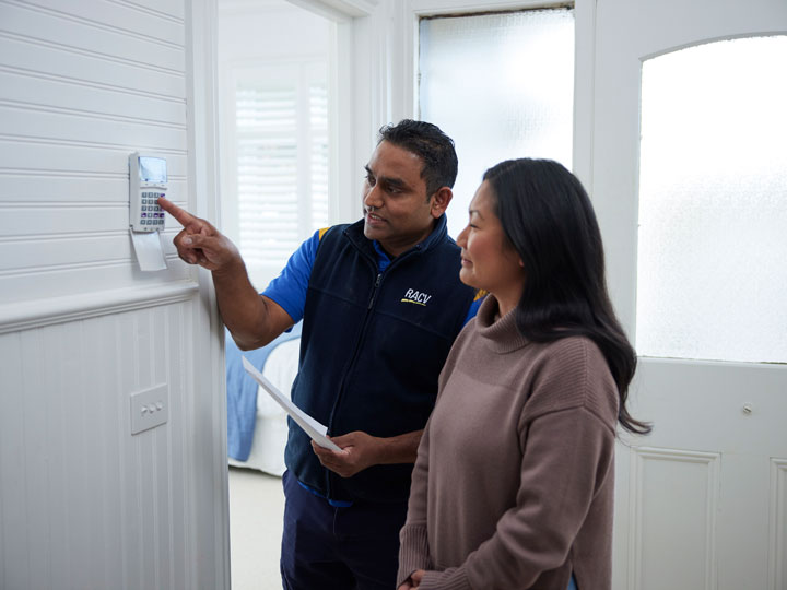 A tradie showing an owner how to use their new alarm