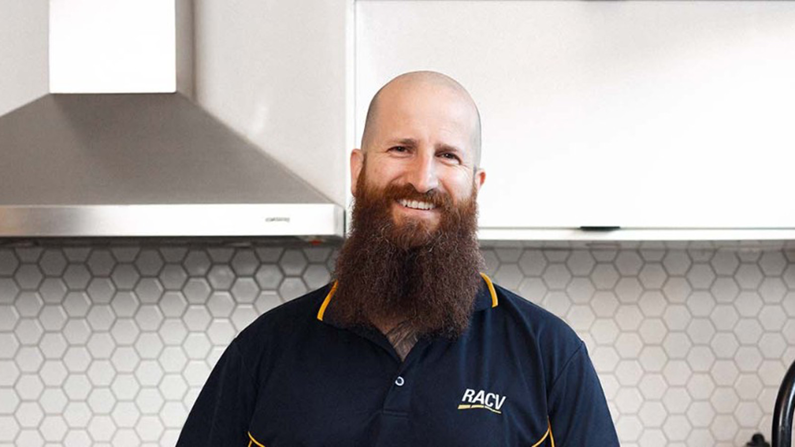 RACV tradesperson standing in kitchen and smiling.