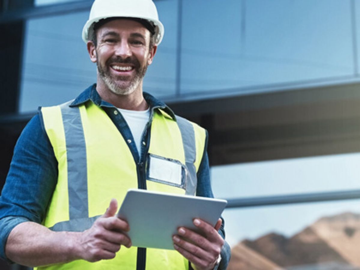 A  smiling building and pest inspector dressed in hi-vis and a hardhart with his clipboard.