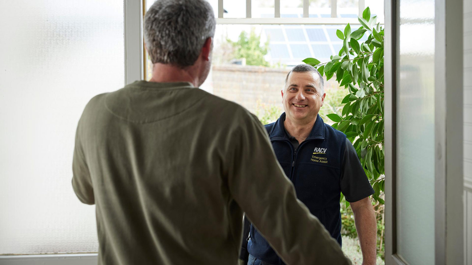 A smiling tradesman greeting his customer at the front door.