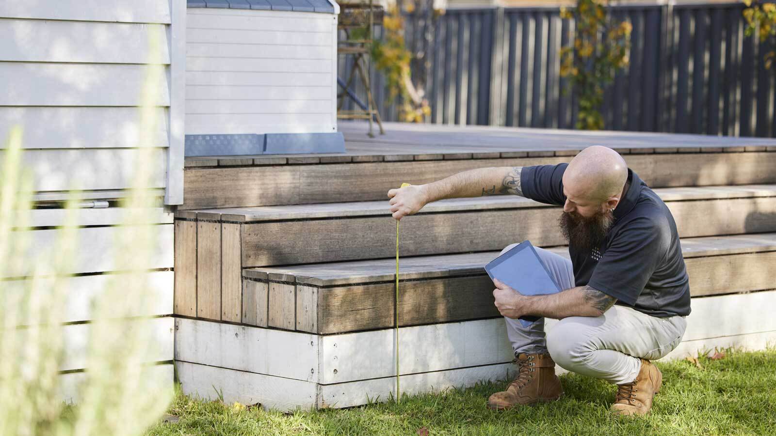 RACV tradesman measuring an outdoor step.