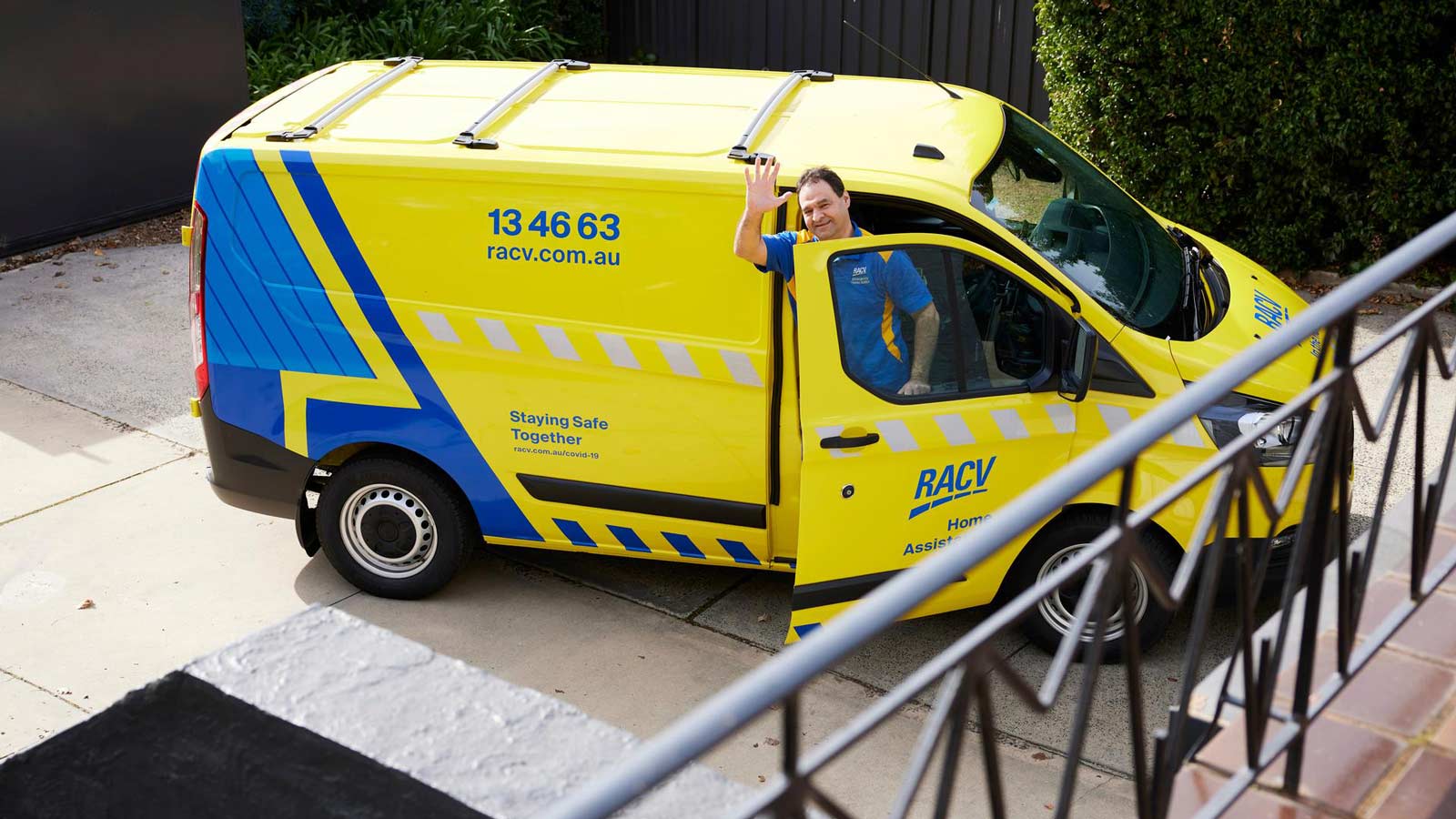 Tradesman waving to customer as he steps out of his van.