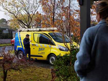 RACV Tradesman in the driveway, holding yellow emergency trades van door open.