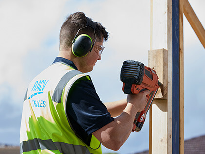 RACV tradie using a nail gun on a timber frame.
