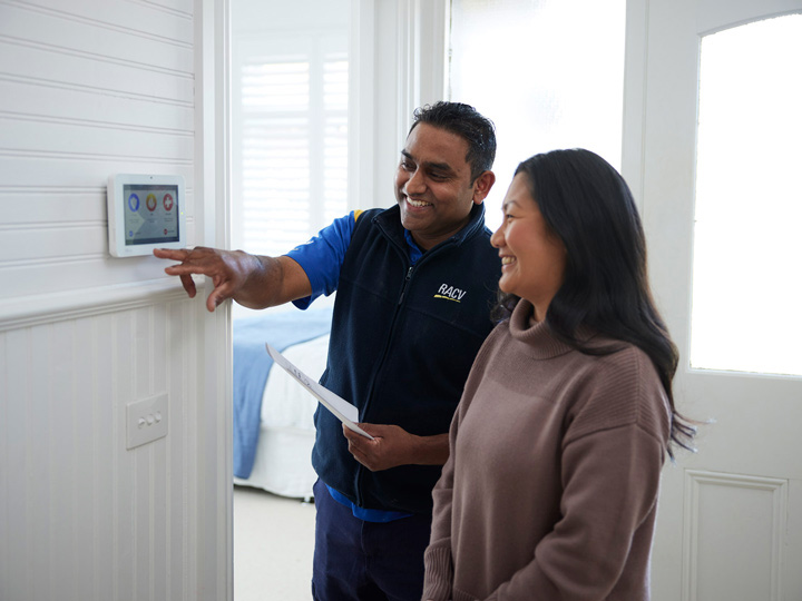 RACV tradesman installing a home security system, while standing next to a happy customer. 