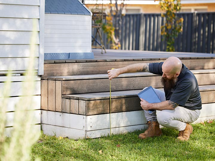 RACV tradesman measuring an outdoor step.