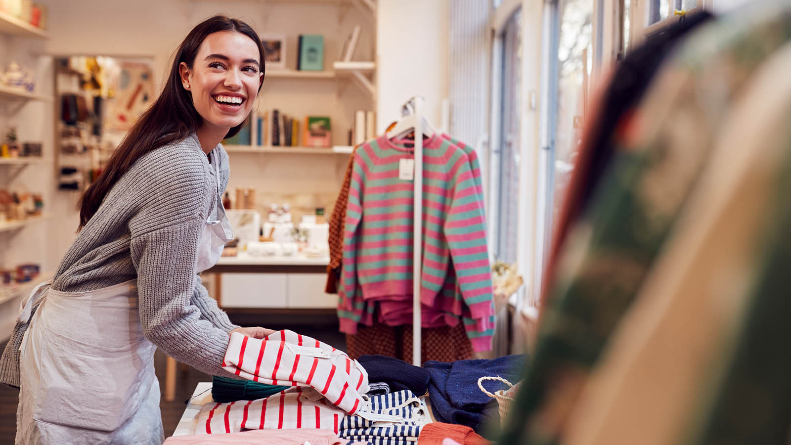Woman in a retail store smiling and holding merchandise.