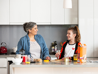 Mother and daughter standing at kitchen bench making sandwiches.