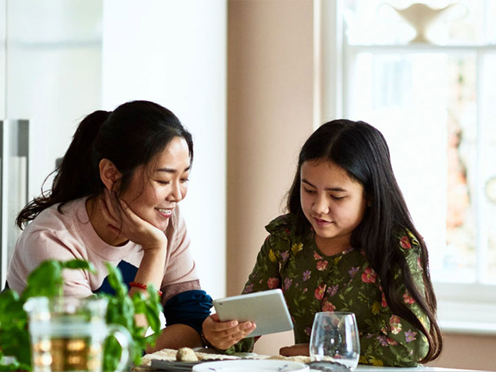 Family sits in kitchen with tablet device