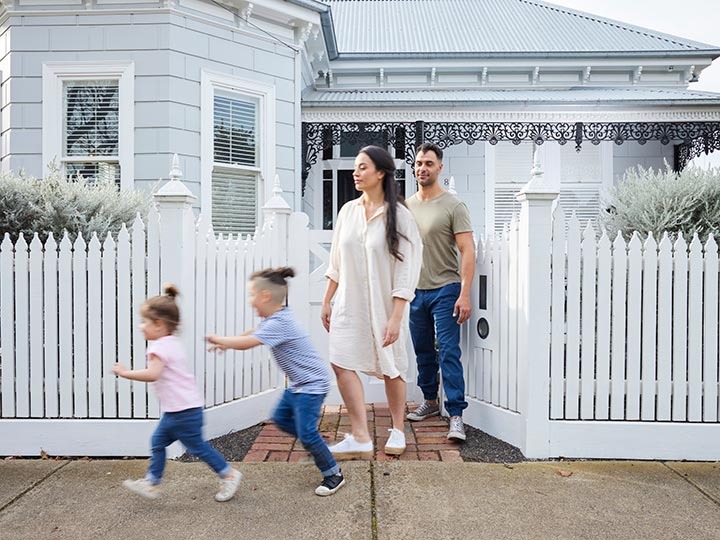 Parents and two young children outside the front of their home.