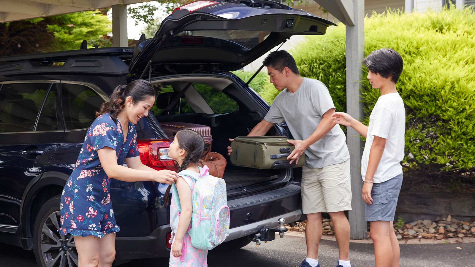 Family putting suitcases in their car boot, in preparation for a holiday..