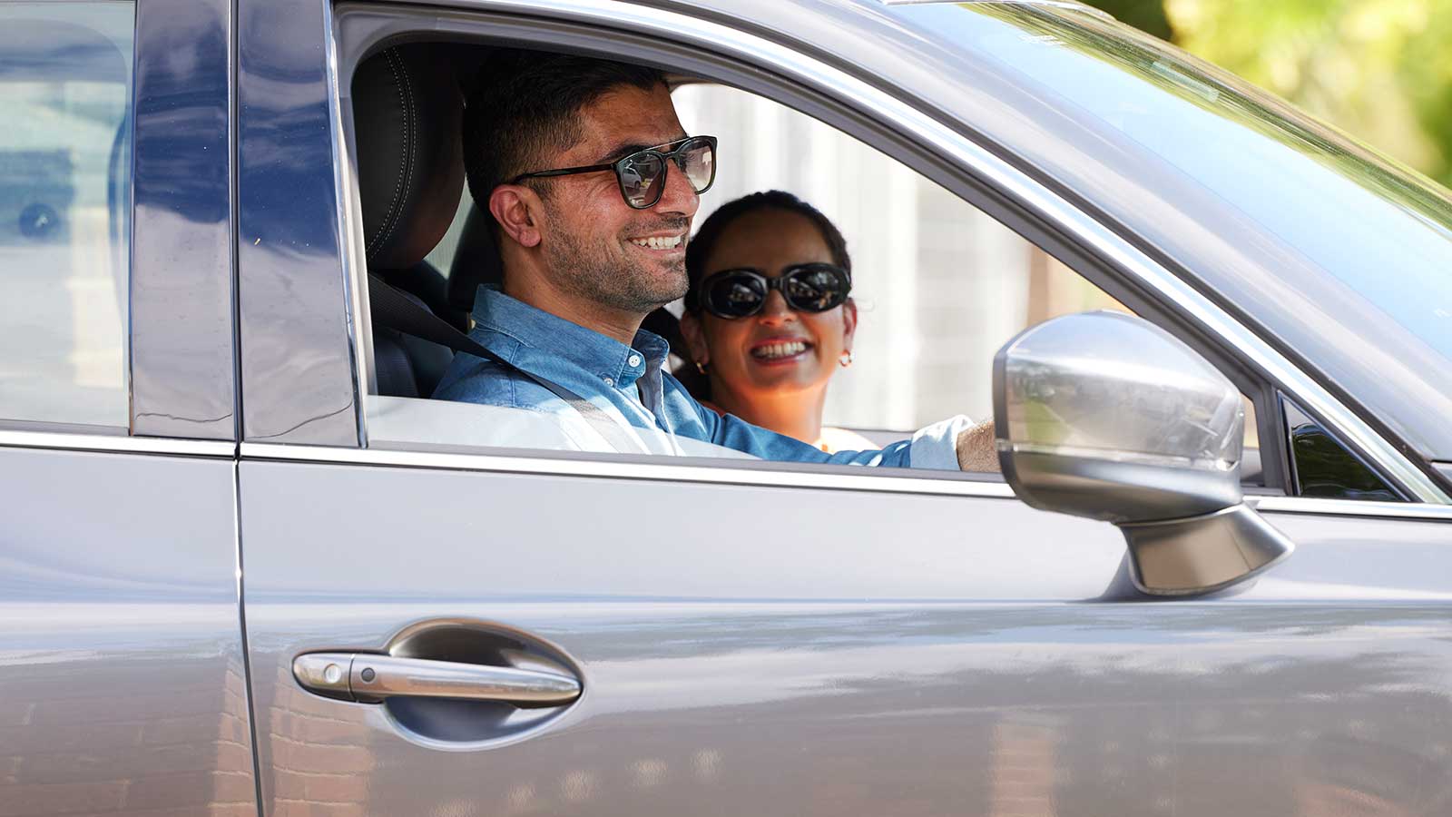 Smiling couple in a car, with the windows down. 