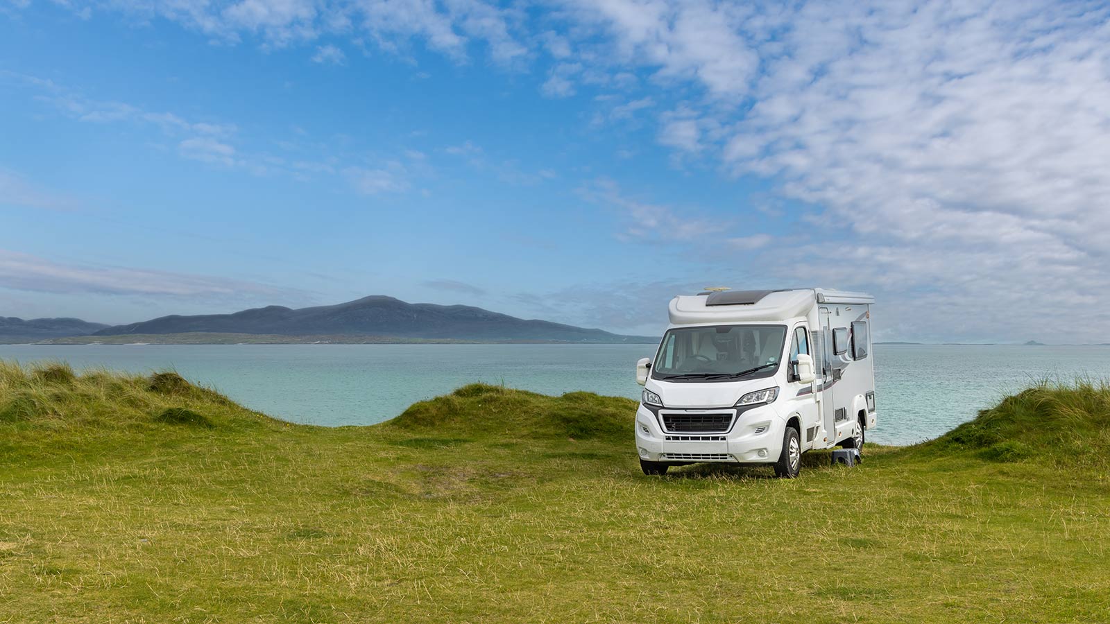 Motorhome parked on lush grass by the ocean.