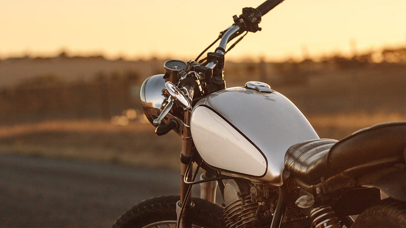 Vintage black and silver motorcycle parked in front of a picturesque sunset.