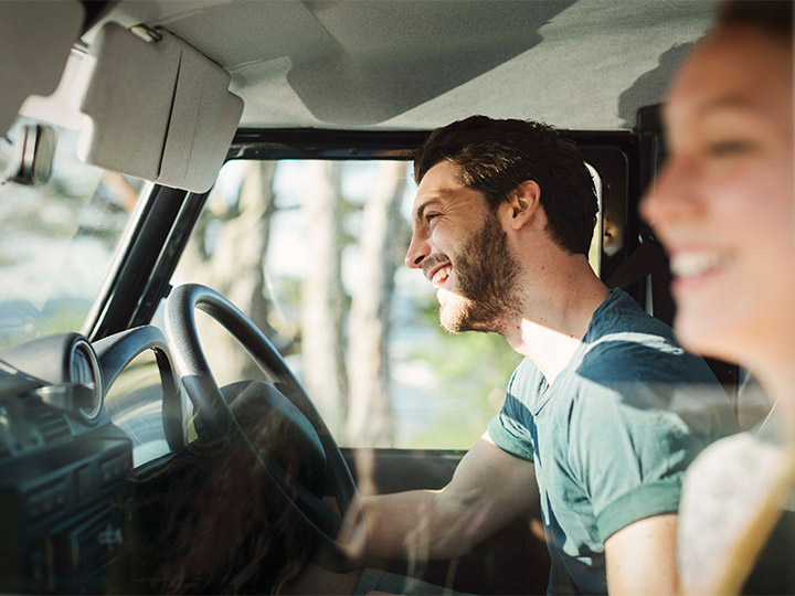 A couple sitting in a car and laughing together.