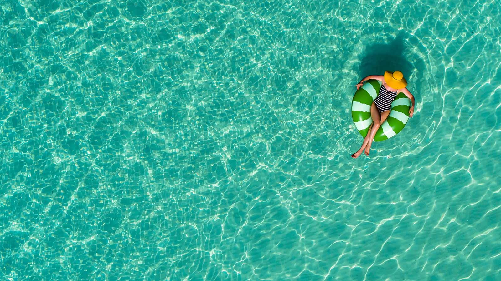 Woman floating in a pool using a floating donut. 