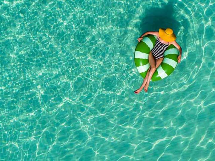 Aerial view of a woman floating in an inflatable ring in a large pool.