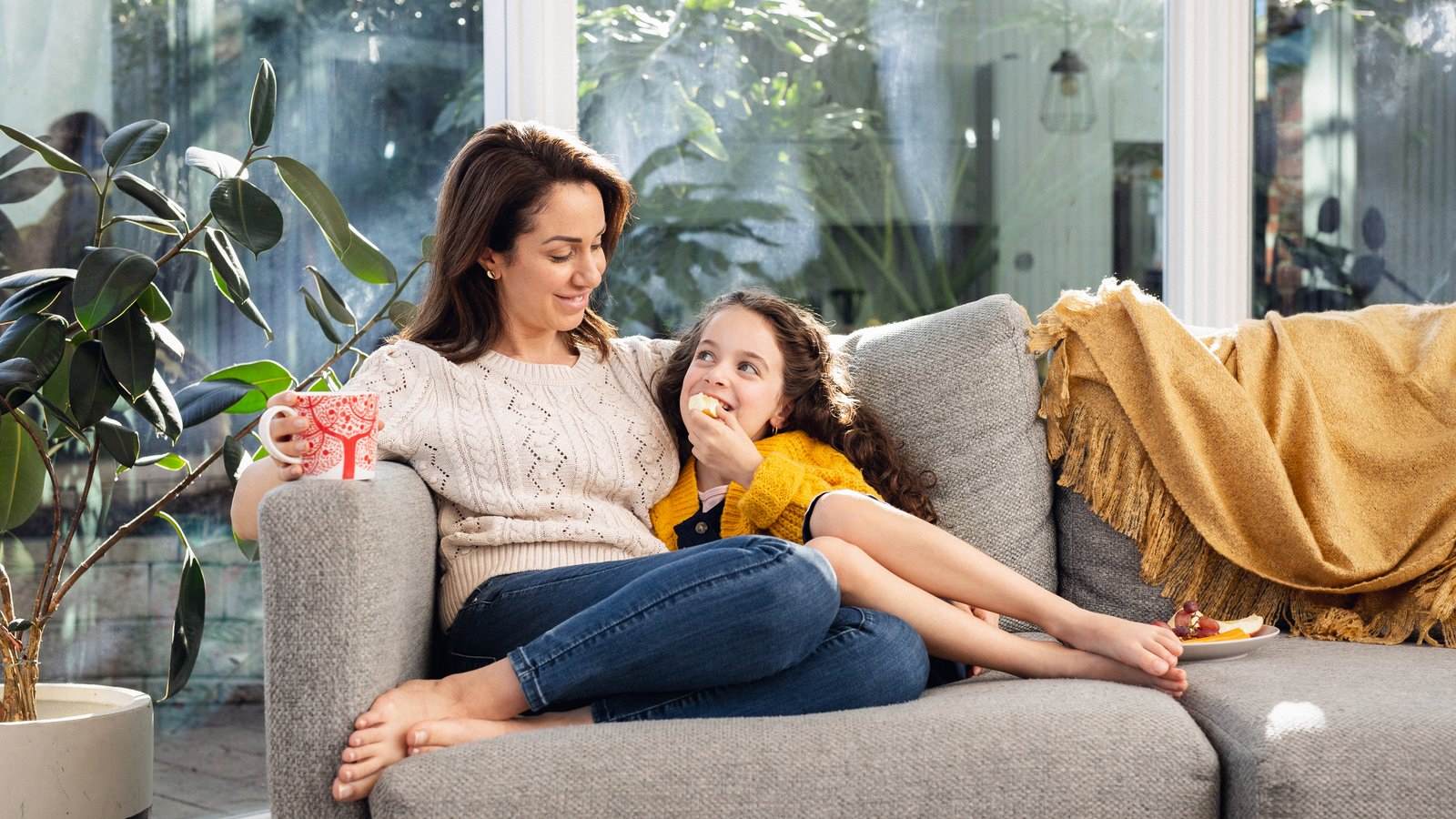 Mum and young daughter relaxing on couch