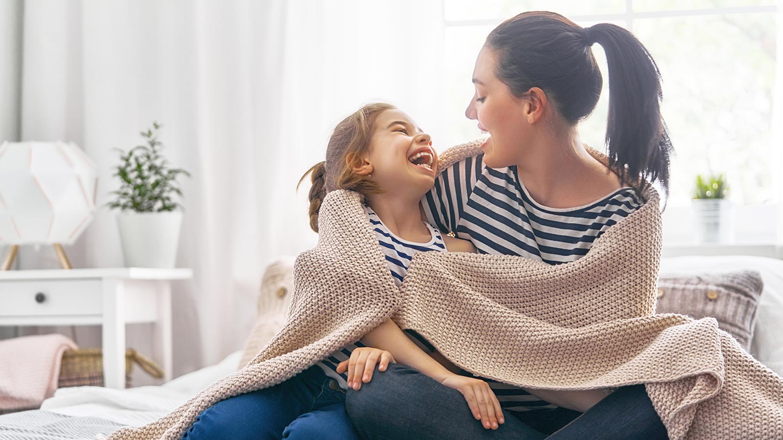 Mother and child wrapped in blanket at home.