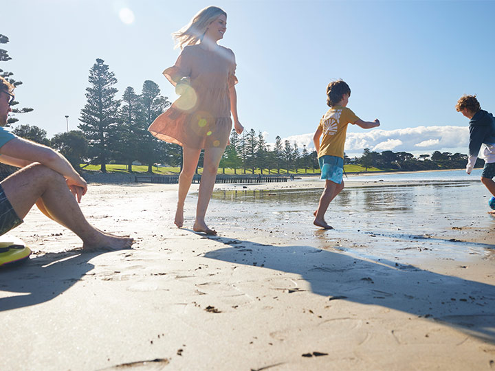 A family running and playing together on the beach.