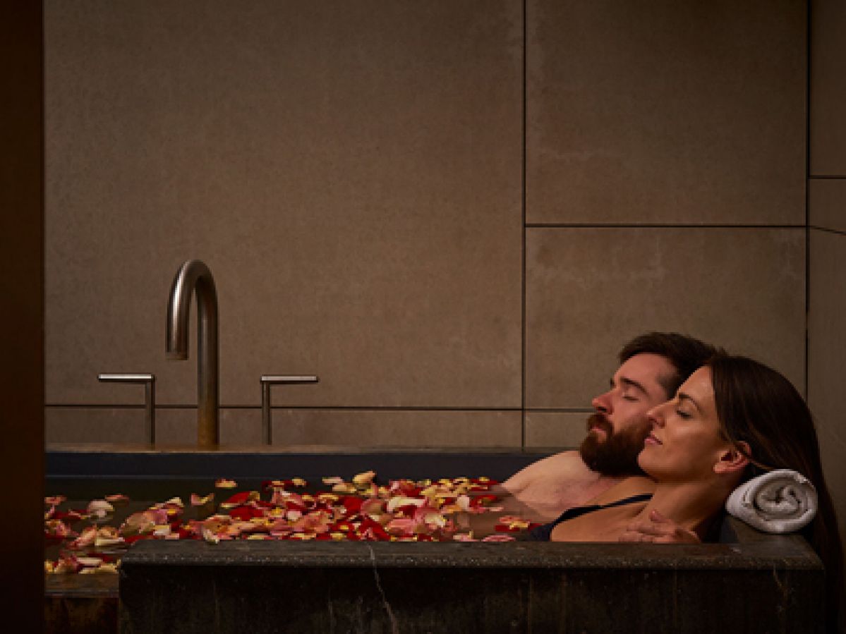 A couple relaxing in a bath with flower petals. 