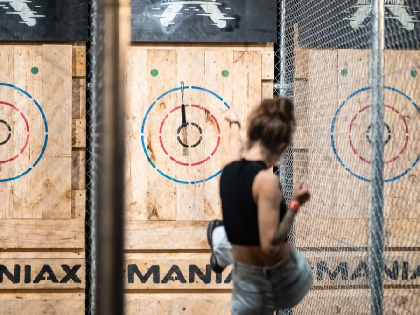 Person throwing an axe at a wooden wall