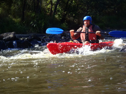 A man white water rafting in a red kayak