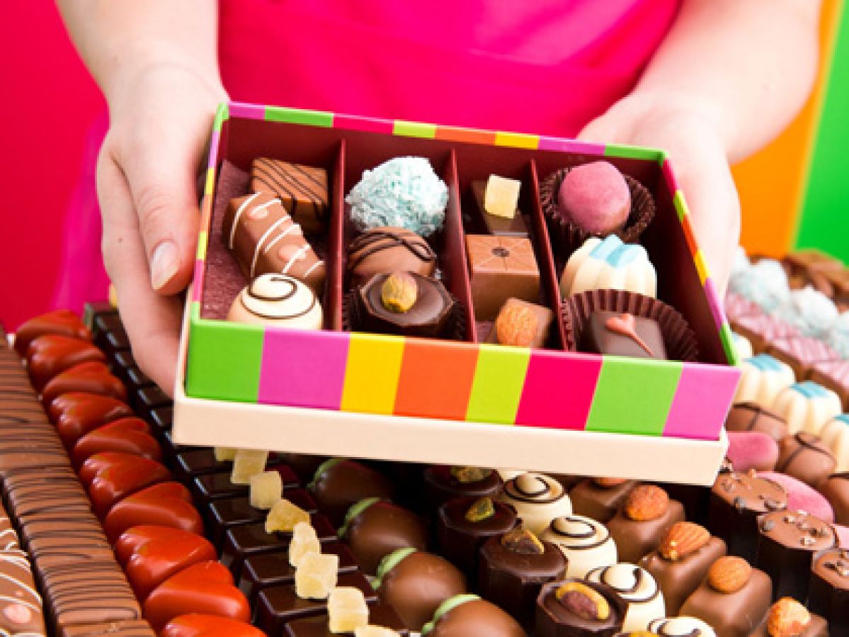 Woman holding a colourful box of chocolates.
