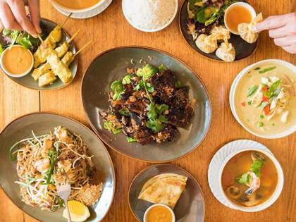 Several Thai meals plated and on a table. 