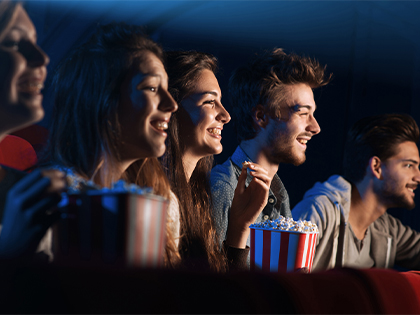 Group of friends watching a movie in the cinemas and eating popcorn. 