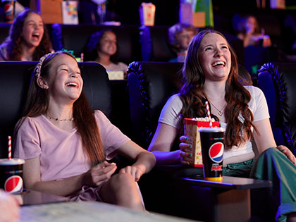 Mother and daughter laughing in a cinema
