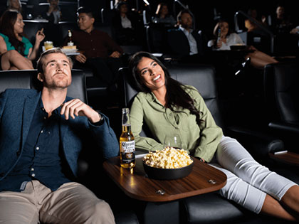 Man and woman in reclining cinema chairs with popcorn
