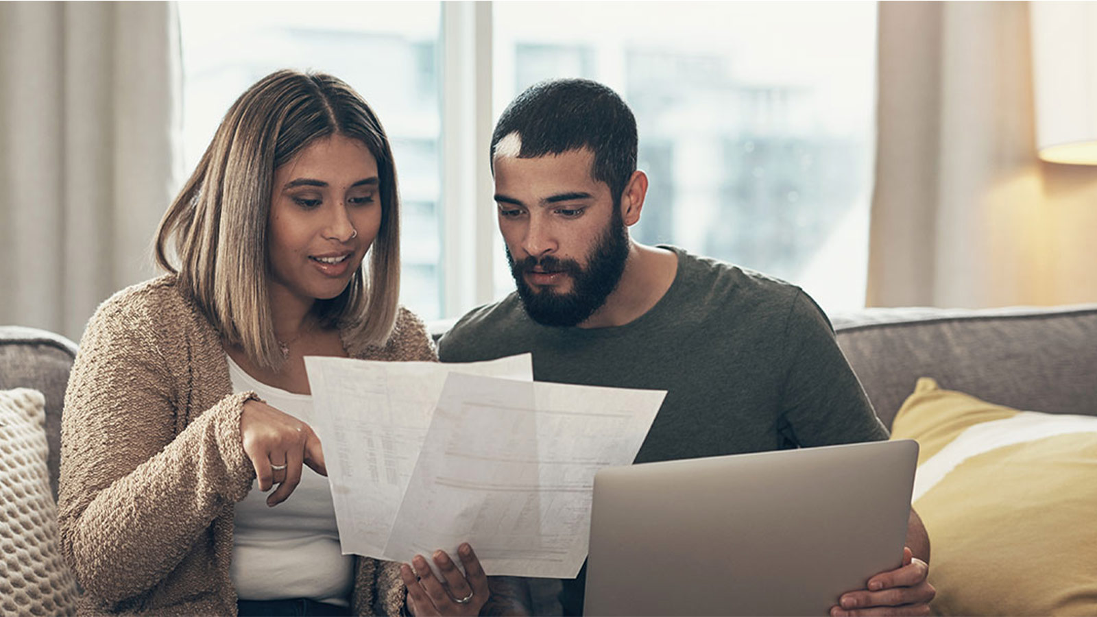 Couple sitting on couch looking at documents.