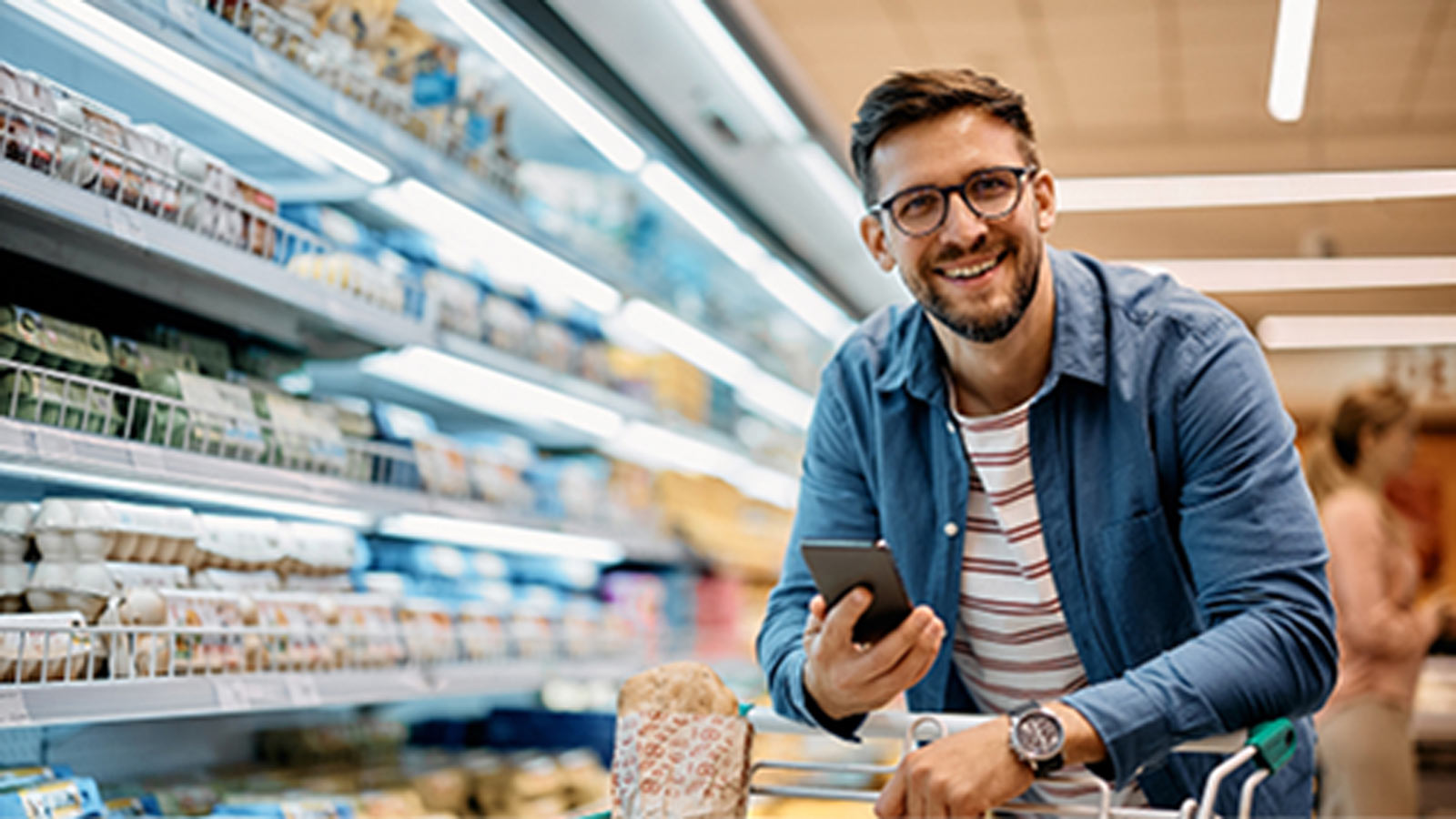 Man looking at his phone while doing a grocery shop