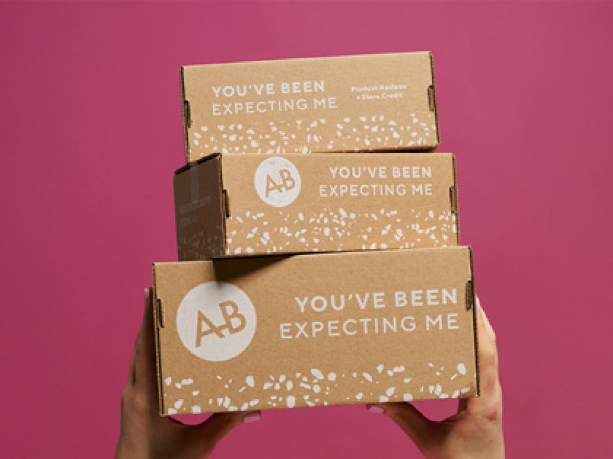 Three Adore Beauty boxes stacked being held up with a pink background