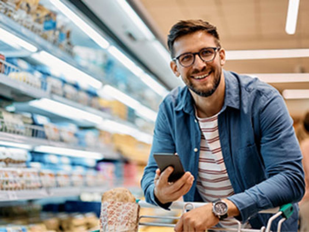Man looking at his phone while doing grocery shop