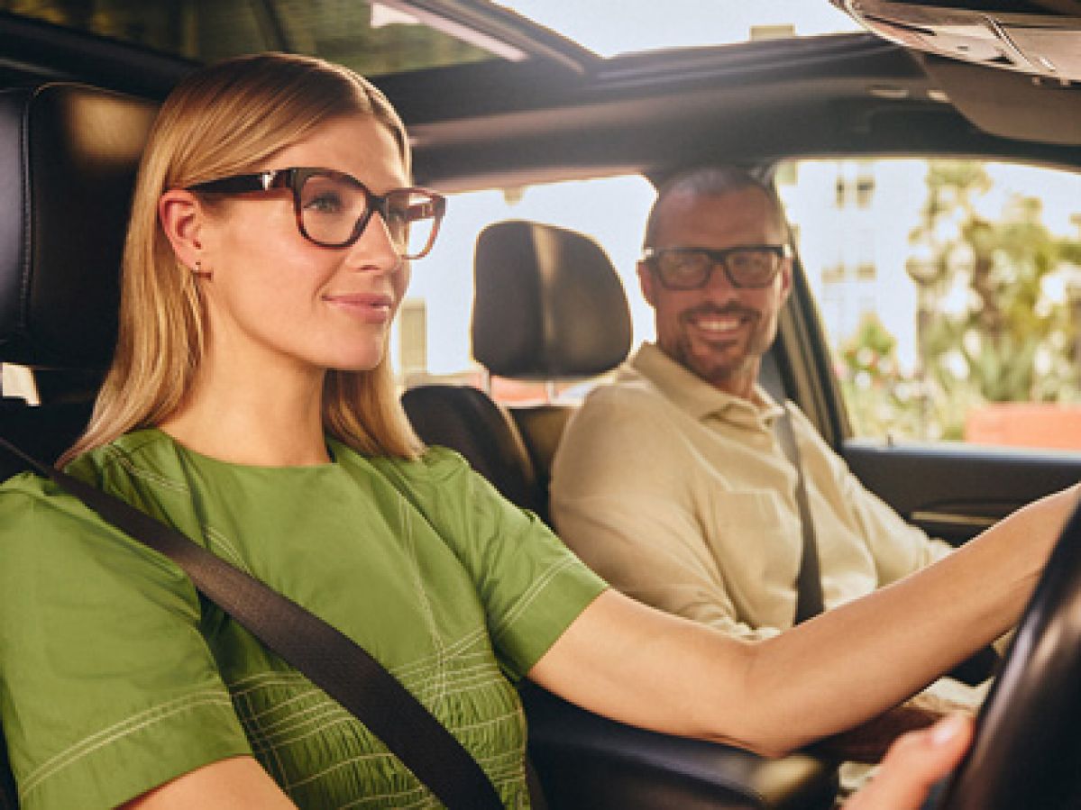 A couple both wearing glasses in a car.