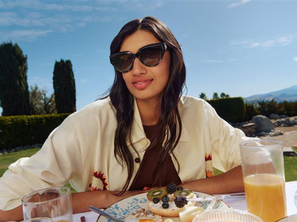 Woman enjoying breakfast outside with her sunnies on.
