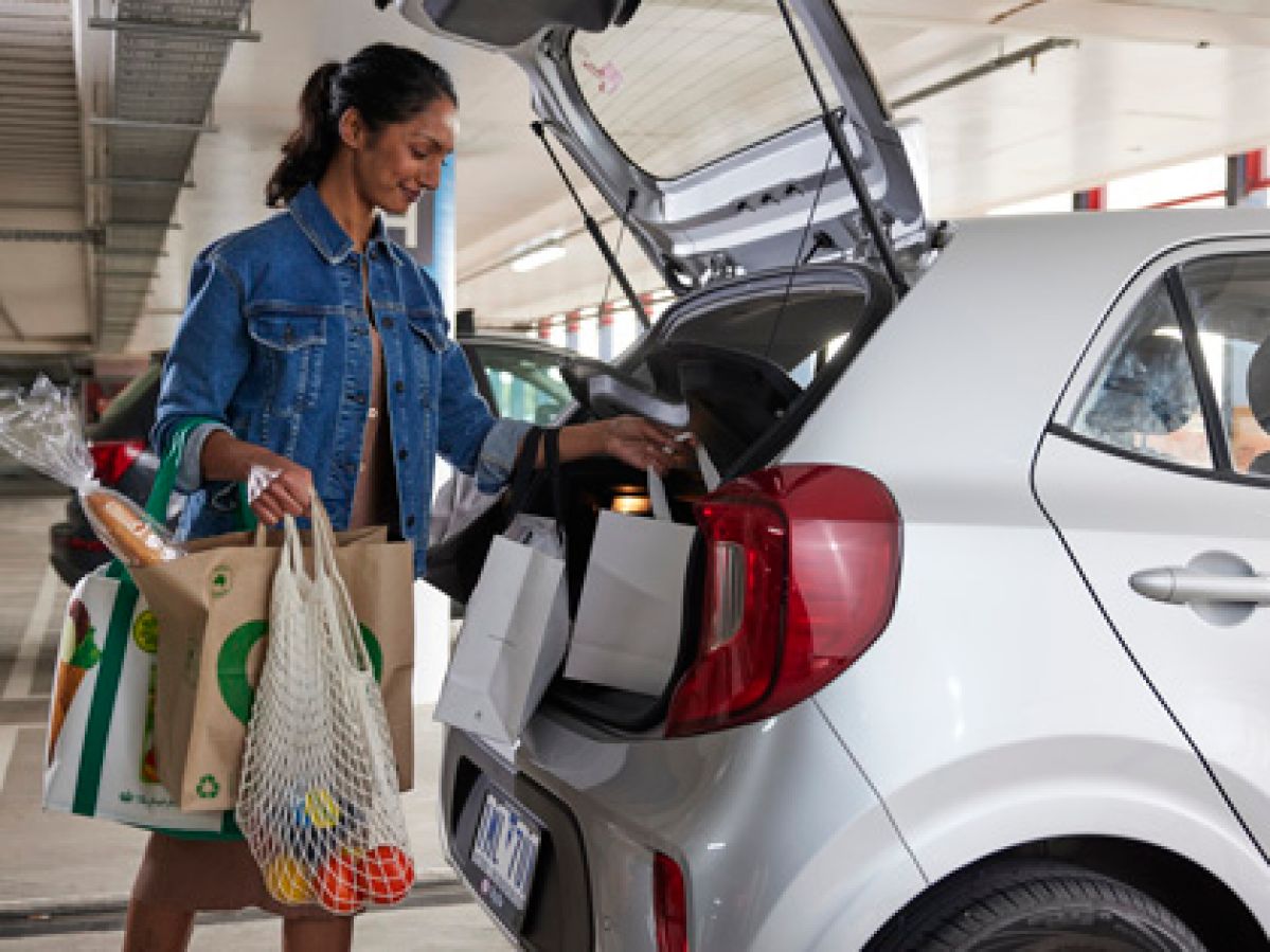 Woman loading bags of groceries into her car.