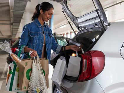 A woman loading groceries from woolies into her boot